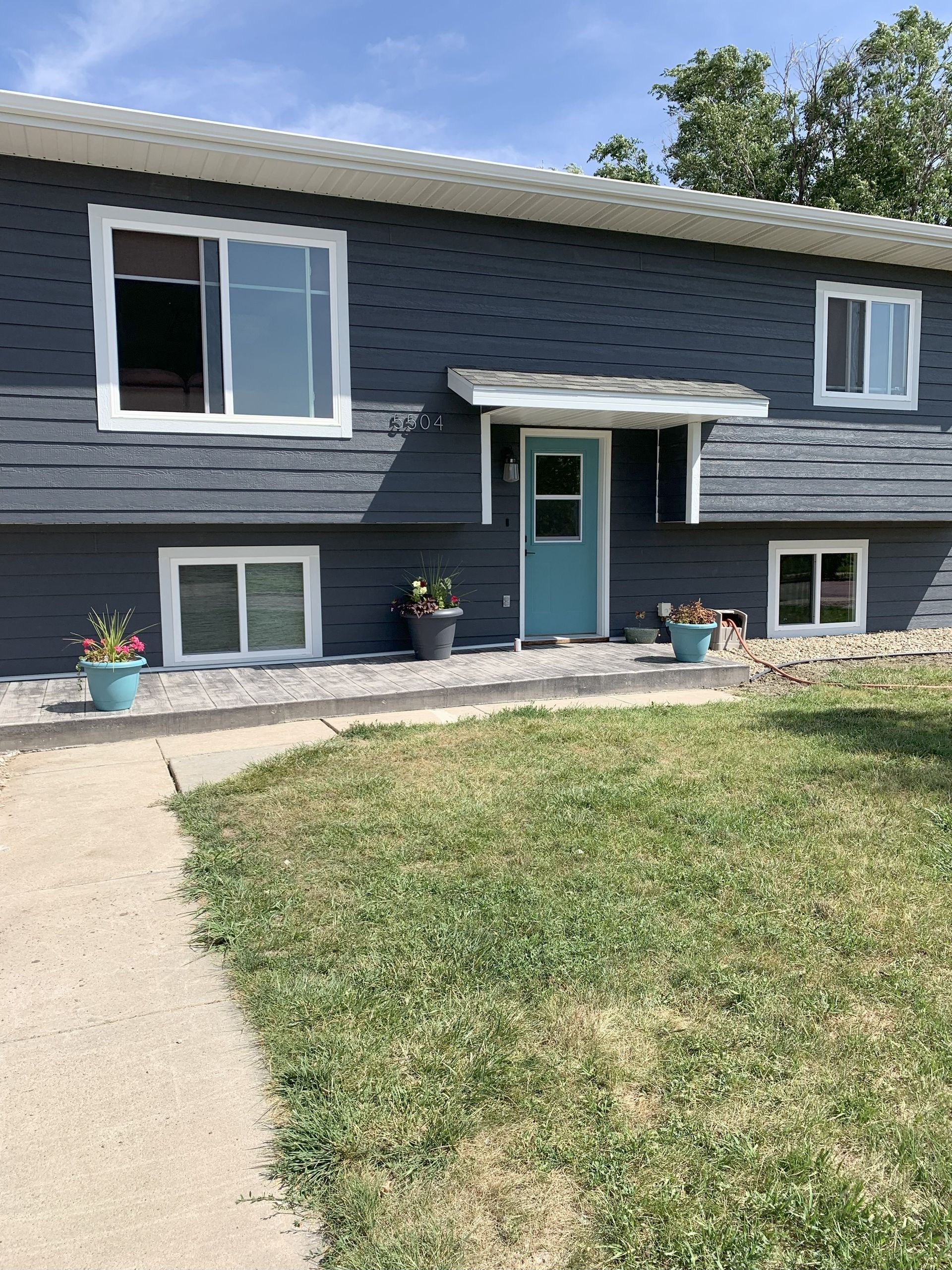 Two-story house with blue siding, white-framed windows, and a teal front door after a Bonn siding and window makeover
